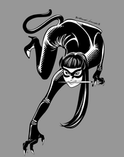 Load image into Gallery viewer, A close-up of the shirt design, featuring a lithe young woman in a catsuit, including tail, crawling toward the camera, printed on it. The woman wears a cat-eye mask and holds a dip pen in her teeth.