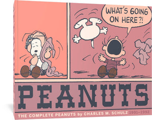 The cover to The Complete Peanuts 1991-1992: Vol. 21 Paperback Edition, which features two panels from a Peanuts comic. In the first, Linus has Snoopy seated on his lap, sucking his thumb, while Linus holds his blanket with his other hand. in the second, Snoopy and the blanket have gone flying as Linus throws out his arms and shouts, "What's going on here?"